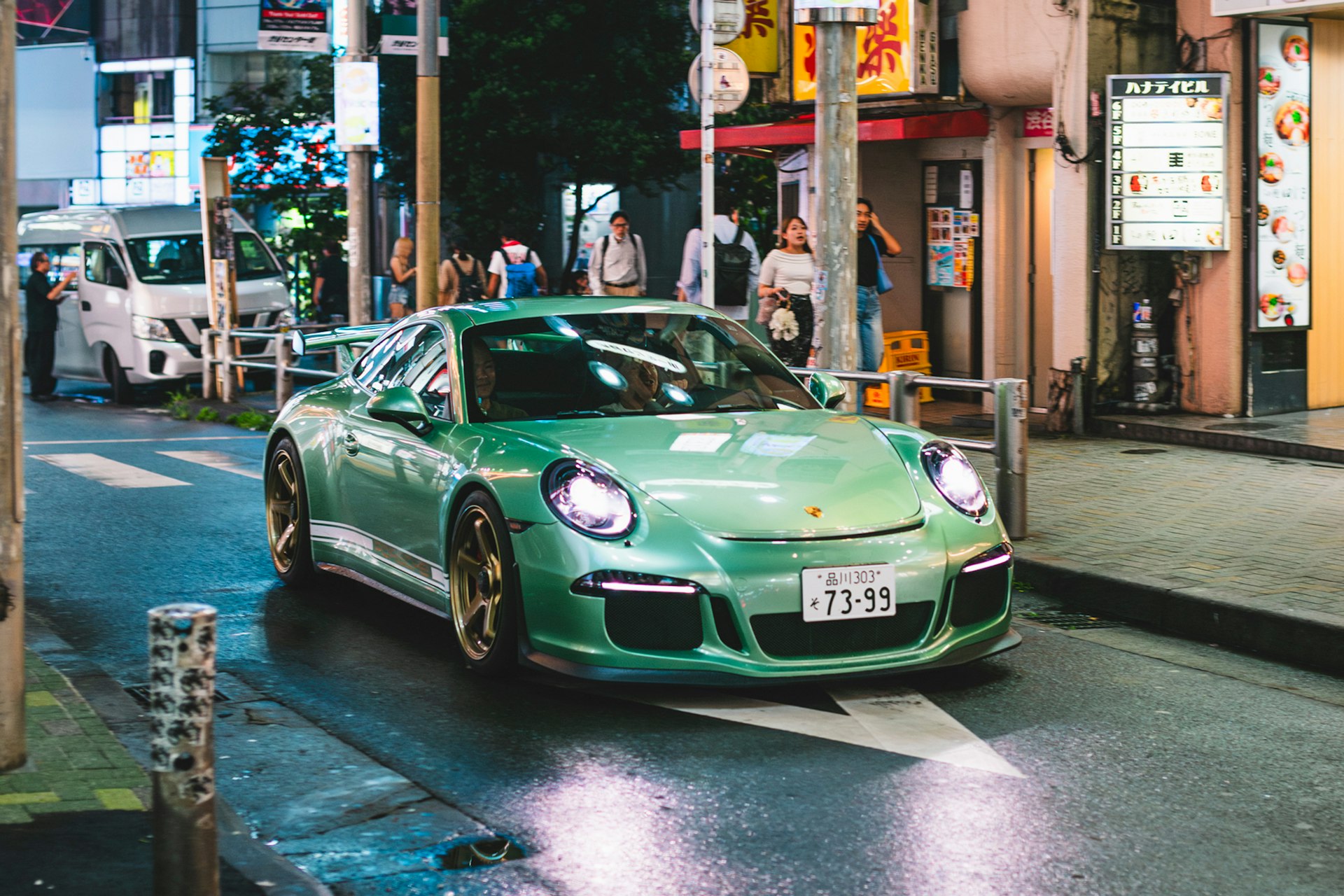 A green sports car driving down a city street
